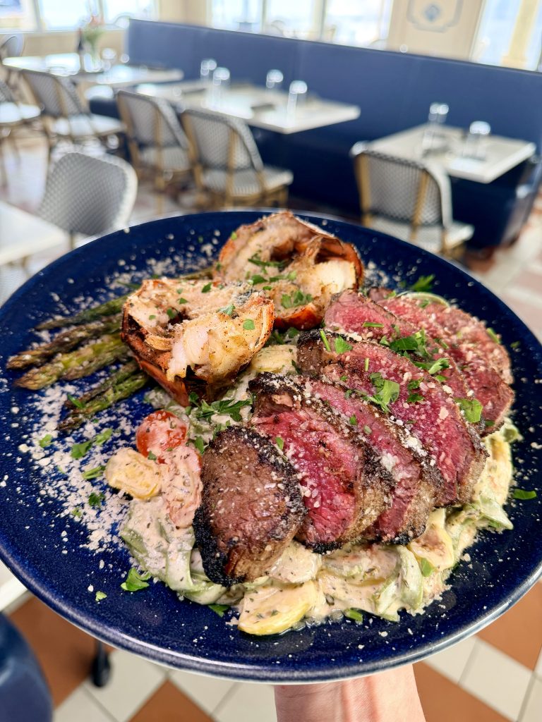 IMG_2779 copy Grilled meat medallions and roasted asparagus on a blue speckled plate with creamy sauce, bringing Italy’s bold, comforting flavors to Pass Christian.