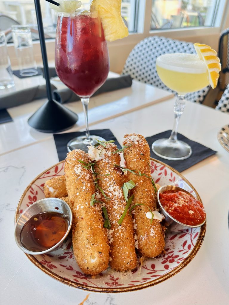 IMG_3349 copy Breaded Italian bites on a patterned plate with a red cocktail and a yellow citrus drink topped with lemon garnish, at Field’s Italian Pass Christian.